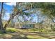 Gray farmhouse exterior nestled under large oak tree at 14900 Coker Gully Rd, Myakka City, FL 34251