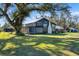 Dark-painted farmhouse with screened porch, surrounded by lush green lawn and mature trees at 14900 Coker Gully Rd, Myakka City, FL 34251