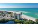 Gorgeous aerial view of a high-rise condo building on a white sandy beach with clear, turquoise water at 19 Whispering Sands Dr # 301, Sarasota, FL 34242