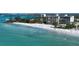 Expansive view of a white sandy beach, turquoise water, and condo buildings in the distance at 19 Whispering Sands Dr # 301, Sarasota, FL 34242