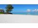 Expansive beach view showcasing the pristine white sand meeting the clear turquoise water under a blue sky at 19 Whispering Sands Dr # 301, Sarasota, FL 34242