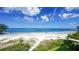 Beautiful view of a white sand beach and the blue ocean under a partly cloudy sky at 19 Whispering Sands Dr # 301, Sarasota, FL 34242
