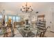 Bright dining room with a chandelier, glass table and seating for six with views to the living room and balcony at 19 Whispering Sands Dr # 301, Sarasota, FL 34242