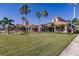 Beautiful clubhouse features lush green lawns, sidewalks, and tropical palm trees under a clear blue sky at 2479 Brassica Dr, North Port, FL 34289