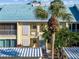 Building exterior featuring light-yellow walls, teal roof, and palm trees at 414 Cerromar S Cir # 249, Venice, FL 34293