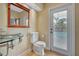 Modern bathroom with glass sink, toilet, and door leading outside at 4673 Deer Creek Blvd, Sarasota, FL 34238