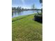 Spacious backyard with lake view, lush grass, and mature landscaping at 5947 Benevento Dr, Sarasota, FL 34238