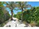 Charming pathway lined with palm trees and lush landscaping leading to beach at 5981 Emerald Harbor Dr, Longboat Key, FL 34228