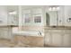 Spacious bathroom featuring dual sinks, granite countertops, white cabinets, large bathtub and neutral color scheme at 4742 Balboa Park Loop, Bradenton, FL 34211