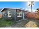 Dark gray house with light green door, wood fence, and a palm tree in front at 611 E Virginia Ave, Punta Gorda, FL 33950