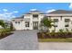 Two-story home features a light-colored facade, paver driveway, and lush landscaping at 624 Blue Shell Loop, Sarasota, FL 34240