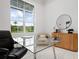 Bright office space featuring a glass desk, comfortable chair, and natural light from a large window with backyard views at 624 Blue Shell Loop, Sarasota, FL 34240
