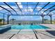 A screened pool overlooks a lake with palm trees and a beautiful blue sky at 624 Blue Shell Loop, Sarasota, FL 34240