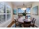 Cozy dining area with a round table, large windows, and a view to the pool and lake at 7115 Callander Cv, Lakewood Ranch, FL 34202