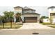 Two story blue home featuring a large garage, well manicured lawn, and palm trees at 731 Cristelle Jean Dr, Ruskin, FL 33570