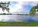 Picturesque lake view surrounded by lush greenery and community homes under a bright, cloud-dotted sky at 9514 Colonial Dr, Bradenton, FL 34210