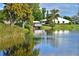 Scenic lake view featuring waterfront homes, a covered dock, and abundant greenery at 9514 Colonial Dr, Bradenton, FL 34210