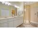 Bathroom with double sinks, white cabinets, large mirrors, and a glass enclosed shower at 9623 Sea Turtle Ter # 201, Bradenton, FL 34212