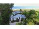 A high-angle showcases the property's location amidst lush greenery, with glimpses of the ocean and a beautiful shoreline at 6061 Gulf Of Mexico Dr, Longboat Key, FL 34228