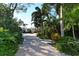 Brick driveway lined with lush greenery and tropical plants leading up to a beautiful house, creating a welcoming approach at 6061 Gulf Of Mexico Dr, Longboat Key, FL 34228