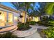 The exterior features lush tropical landscaping, a curved paver walkway, and warm lighting that enhance the home's appeal at 6061 Gulf Of Mexico Dr, Longboat Key, FL 34228