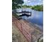 Private wooden dock on tranquil lake with a concrete boat ramp and a red gate at 6504 Lincoln Rd, Bradenton, FL 34203