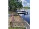 Still lake and wooden dock view, with a concrete ramp and red metal gate at 6504 Lincoln Rd, Bradenton, FL 34203