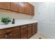 Practical laundry area features ample counter space, wood cabinetry, and storage for efficient organization at 19864 Petrino St, Venice, FL 34293