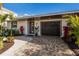 Inviting home exterior featuring a landscaped walkway, modern garage door, and lush tropical plants at 213 83Rd St # East, Holmes Beach, FL 34217