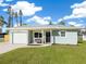 Newly built home featuring a light green exterior, a white garage door, and a well-manicured lawn at 3305 New England St, Sarasota, FL 34231