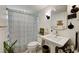 Clean bathroom with pedestal sink, striped shower curtain, and updated vanity at 4330 Falmouth Dr # 108, Longboat Key, FL 34228