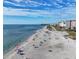 Expansive beach with people enjoying the sun and surf, backed by beachfront buildings under a blue sky at 461 Nokomis S Ave, Venice, FL 34285