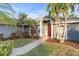 Inviting single-story home featuring lush landscaping and a vibrant red front door at 4877 Post Pointe Dr, Sarasota, FL 34233