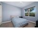 Cozy bedroom with a queen bed, soft blue bedding, and a window with a tropical view at 942 Preservation St, Bradenton, FL 34208