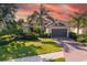 Beautiful home featuring a well-manicured lawn, palm trees, and a brick driveway under a captivating sky at 942 Preservation St, Bradenton, FL 34208