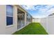 Home's backyard featuring a screened-in lanai and lush green grass, enclosed by a white fence at 5307 52Nd W Ave, Bradenton, FL 34210