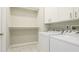 Bright laundry room featuring tile floors, washer, dryer, upper cabinets, and shelf space at 5307 52Nd W Ave, Bradenton, FL 34210