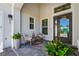 Inviting front entrance with a covered porch, seating, and a modern glass-paneled front door at 8328 Sea Glass Ct, Sarasota, FL 34240
