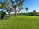 Spacious grassy area with mature trees and a park bench at 8752 Bellussi Dr, Sarasota, FL 34238