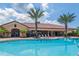 Community pool and clubhouse with palm trees and lounge chairs at 8752 Bellussi Dr, Sarasota, FL 34238