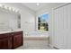 Bright bathroom featuring a soaking tub with tile surround and a window offering serene outdoor views at 1743 Pinyon Pine Dr, Sarasota, FL 34240
