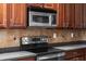 Modern kitchen featuring stainless steel microwave and stove with dark countertops and tile backsplash at 1743 Pinyon Pine Dr, Sarasota, FL 34240