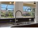 Close-up of a kitchen sink with stylish faucet, dark countertops, and a view of the backyard through the window at 1743 Pinyon Pine Dr, Sarasota, FL 34240