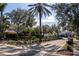 A quiet street view framed by mature trees and manicured landscaping leading up to an elegant home at 1743 Pinyon Pine Dr, Sarasota, FL 34240