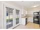 White kitchen cabinets, black appliances, and French doors to backyard at 2410 13Th W St, Palmetto, FL 34221
