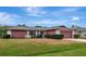 Red and white ranch home with a large lawn and brick paver driveway at 4423 Meadow Creek Cir, Sarasota, FL 34233