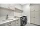Well-appointed laundry room features modern washer and dryer, cabinets and herringbone tile accent wall at 4815 Featherbed Ln, Siesta Key, FL 34242