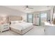 Bright main bedroom with a tufted headboard, neutral decor, and large windows with stylish curtains at 5225 Grove Mill Loop, Bradenton, FL 34211