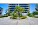 Elegant condominium exterior showcasing lush tropical landscaping at the entrance at 575 Sanctuary Dr # A303, Longboat Key, FL 34228