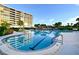 Resort-style swimming pool with lane lines, surrounded by palm trees and overlooking a condominium building at 575 Sanctuary Dr # A303, Longboat Key, FL 34228